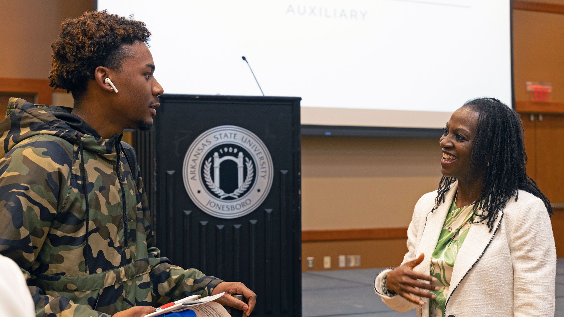 Inside Centennial Hall, a student is speaking with a smiling woman