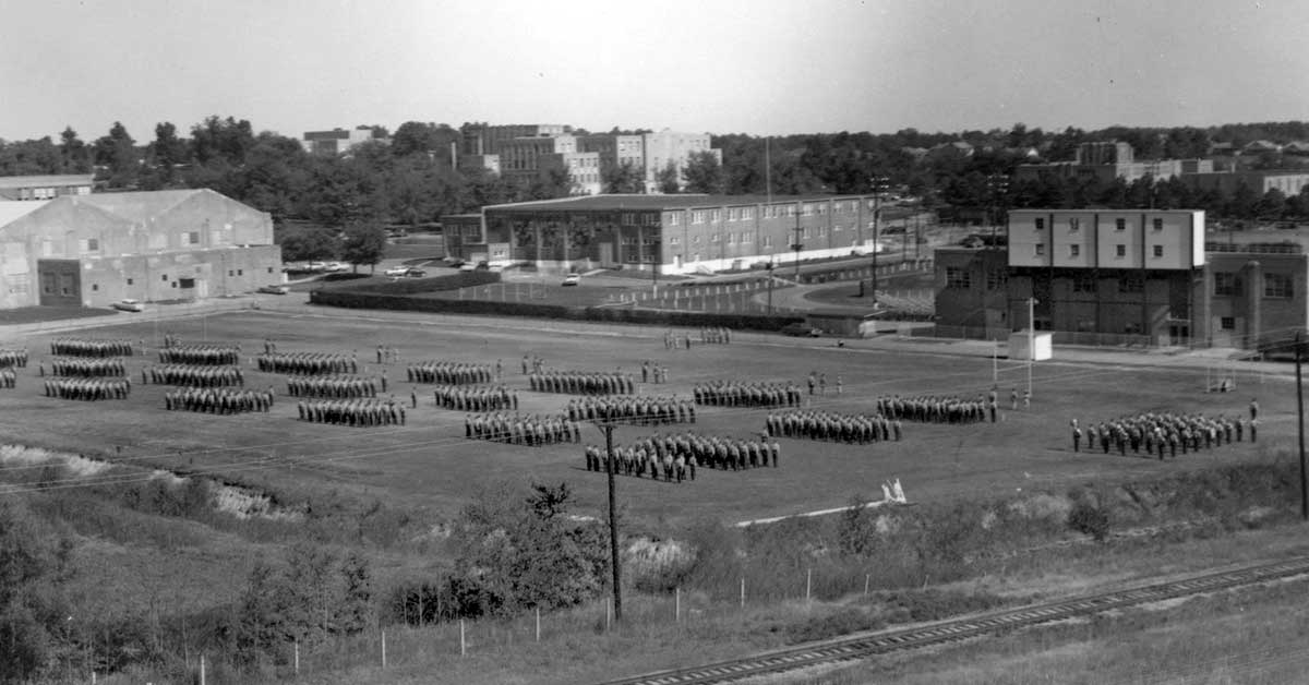 ROTC annual formal inspection (AFI), about 1965, at the drill field where the Health, Physical Education and Sport Sciences Building now stands. Wilson Hall, Computer Science and Mathematics Building and Arkansas Hall are among the buildings in the background.